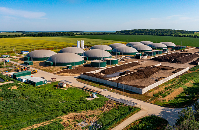Biogas station at the green large field. Distillation process is used to produce bio gas at station. View from above
