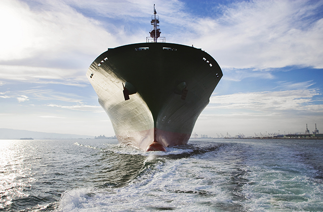 Bow view of cargo ship sailing out of port.